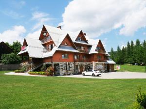 a large house with a car parked in front of it at Dom Wczasowy Kazik in Maniowy