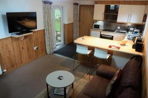 a living room with a couch and a kitchen at Waterfall Lodge - private waterfall and sauna in Killin