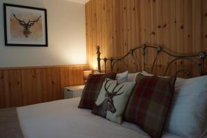 Un dormitorio con una cama con una cabeza de ciervo en las almohadas en Waterfall Lodge - private waterfall and sauna en Killin