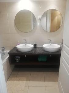 a bathroom with two sinks and two mirrors at Appart Alexina, 2mn à pieds de la plage de BOUCAN-CANOT in Saint-Gilles-les-Bains