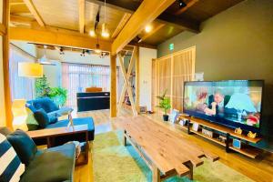 a living room with a large flat screen tv at 48坪！道後温泉付近駐車場有り清潔さと設備の充実さが高評価 大切な家族仲間と広々とくつろげます in Matsuyama