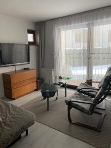 弗瓦迪斯瓦沃沃的住宿－Apartament Patio 50 m od plaży，一间带电视和玻璃桌的客厅