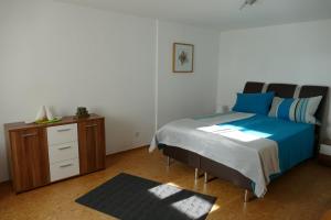 a bedroom with a bed and a dresser with blue sheets at Aktiv-Ferienwohnung "Snow & Bike"- Zentral zwischen Winterberg und Willingen in Winterberg