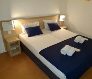 a bedroom with a large bed with two towels on it at Budget Hotel Melun Sud - Dammarie Les Lys in Dammarie-lès-Lys