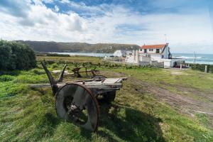 un viejo carro sentado en la hierba cerca del océano en Casa da Vasca, en Malpica de Bergantiños