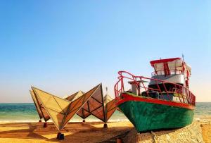 a boat sitting on the beach next to the ocean at Nuweiba Club Resort in Nuweiba
