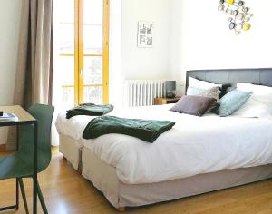 una camera da letto con un grande letto bianco con cuscini sopra di HOTEL DU MIDI a Beaufort-sur-Gervanne