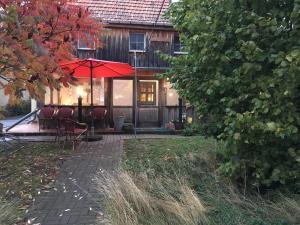 Cette maison dispose d'une terrasse avec des chaises et un parasol. dans l'établissement Pension Elbkiosk, à Kleinzadel