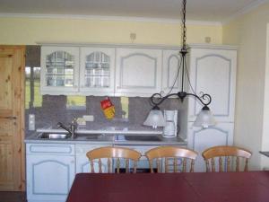 eine Küche mit weißen Schränken und einem Tisch und Stühlen in der Unterkunft Zur alten Schmiede II Haus II in Boltenhagen