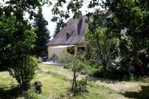 una casa blanca con un patio con árboles y flores en Location de vacance au coeur du Périgord Noir, en Le Bugue