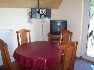 einen Esstisch mit Stühlen und einen TV in der Unterkunft Zur-alten-Schmiede-II (Wohnung oben) in Boltenhagen