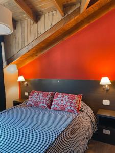 1 dormitorio con 1 cama con pared de color naranja en Espacio Catedral en San Carlos de Bariloche