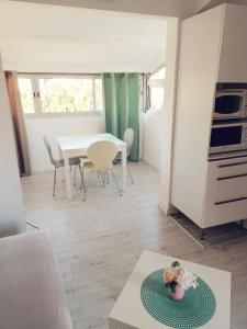 a living room with a table and a white kitchen at Appartement La Pinède in Gruissan