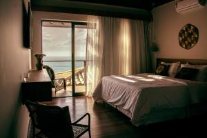 a bedroom with a bed and a view of the ocean at Casa Mirador Boutique Hotel in Búzios