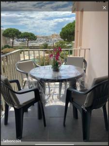 une table en verre avec des chaises et un vase de fleurs sur le balcon dans l'établissement "Le Pharo" 17 Impasse du globe Appartement, au Cap d'Agde