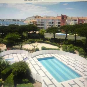 - une vue sur la piscine et le bâtiment dans l'établissement "Le Pharo" 17 Impasse du globe Appartement, au Cap d'Agde