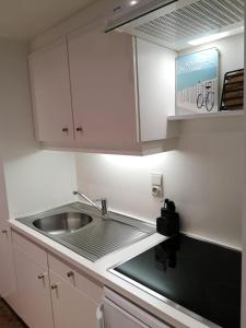 a kitchen with a sink and white cabinets at Zeester en koffie. in Oostduinkerke-Bad