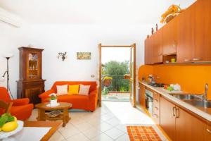 sala de estar con sofá naranja y cocina en Villa Aurora Oasi Verde, en Sorrento