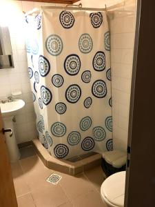 a bathroom with a shower curtain and a toilet at Hostel Elal in El Calafate