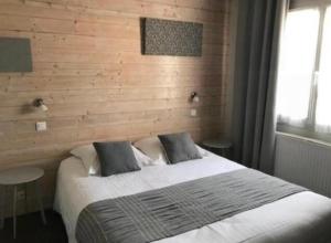 1 dormitorio con 1 cama grande y pared de madera en Hôtel la petite auberge, en Arès