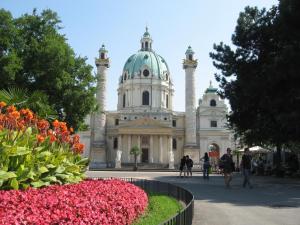 a large white building with a green dome and flowers at Central City Apartment Vienna in Vienna