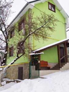 un edificio verde con un banco en la nieve en Boykivska Familiya, en Yaremche