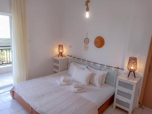 a bedroom with a white bed with two lamps and a window at VILLA MARAVGIA APARTMENT B in Akti Salonikiou