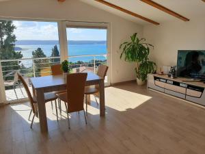 ein Esszimmer mit einem Tisch und Stühlen sowie einem großen Fenster in der Unterkunft Red Rose Apartment in Portorož