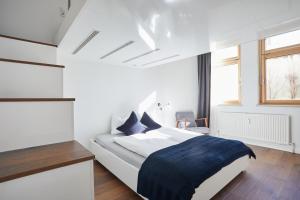 a white bedroom with a large bed with a blue blanket at Maria und Joseph Apartments in Innsbruck