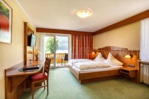 a hotel room with a bed and a desk and a desk at Haus Jäger Ferienwohnungen mit Indoor-Pool inkl. Chiemgaukarte in Ruhpolding +41 photos