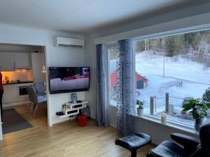a living room with a television and a large window at Tunold Gård - Kårhus in Mindresunde