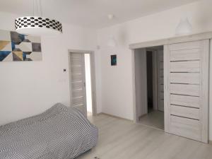 a white bedroom with a bed and a mirror at Apartman TILL in Galanta