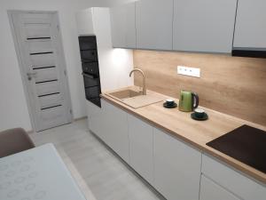 a kitchen with white cabinets and a sink with a green appliance at Apartman TILL in Galanta