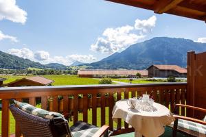 a table on a balcony with a view of a mountain at Haus Jäger Ferienwohnungen mit Indoor-Pool inkl. Chiemgaukarte in Ruhpolding