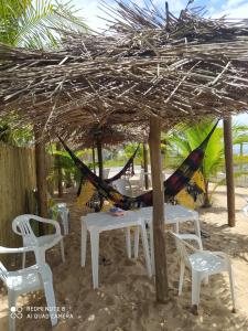 a group of tables and chairs under a straw umbrella at Pousada Dolce Mare in Cacha Pregos