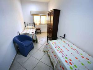 a bedroom with a bed and a blue chair at Fuori Rotta Holiday Home in Maruggio