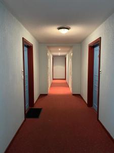 um longo corredor com um tapete vermelho e portas em Le Sporting Land - avec entrée autonome, parking privé & gourmandises offertes ! - em Gaillac