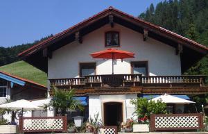a house with a balcony with an umbrella at Haus Neuhäusl inkl. Chiemgaukarte in Ruhpolding