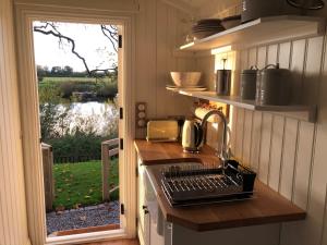 uma cozinha com um lavatório e um fogão com uma janela em The Hut by the River em York