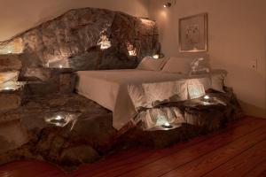um quarto com uma cama numa parede de pedra em Wind Tales em Ermoupoli