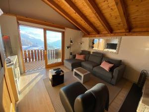 a living room with a couch and a large window at Casa Ansiel - 2.5 Zimmer Ferienwohnung am Sonnenhang von Falera in Falera