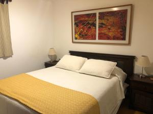 a bedroom with a bed and a painting on the wall at Hostería Zapallar in Zapallar