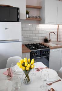 a kitchen with a table with a vase of yellow flowers at Luxus Apartament Sea View Gdynia in Gdynia +23 photos