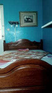 a bedroom with a wooden bed with a blue wall at Los Cuartos Man Pretinha in Tarrafal