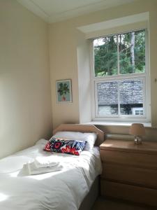 een slaapkamer met een bed met een kussen en een raam bij Great location, quiet yet 5 mins to Bowness centre with walks from the door and parking in Bowness-on-Windermere