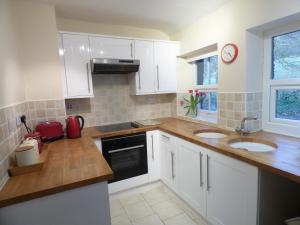 a kitchen with white cabinets and two sinks and a window at Great location, quiet yet 5 mins to Bowness centre with walks from the door and parking in Bowness-on-Windermere