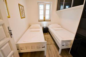 two beds in a small room with a window at Apartment 10 in Villa Petrac in Rab