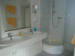 a white bathroom with two sinks and a shower at Hotel Möven-Kieker in Friedrichskoog