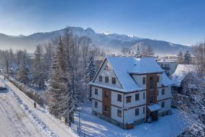 a house with snow on its roof in the snow at Willa Jarosta in Zakopane