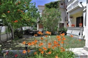 a garden with orange flowers in front of a house at Apartment Peace in Rab